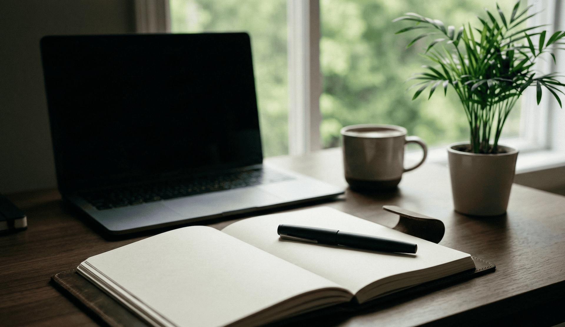 Minimalistischer Remote-Arbeitsplatz mit Laptop, Notizbuch und Pflanze für kreative Digitalagentur-Arbeit